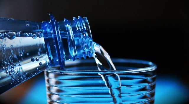 Wasserflasche füllt Wasser in ein Glas.